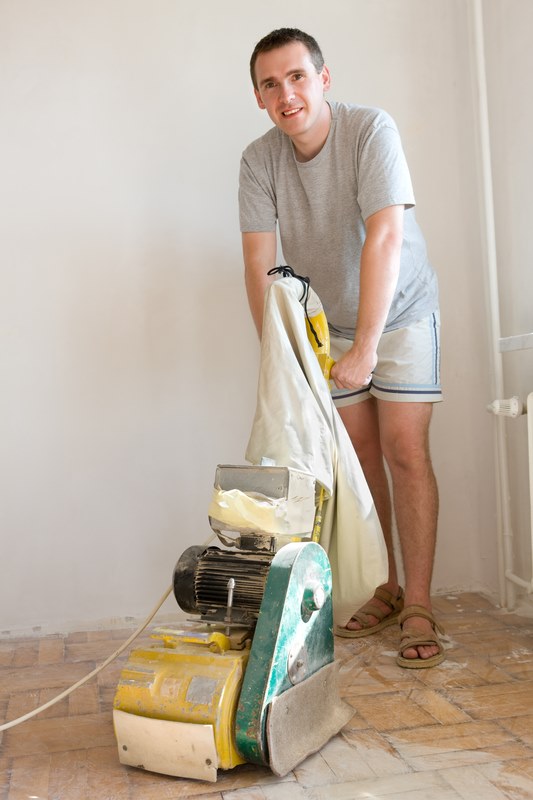 Man sanding a wooden floor with a dust free floor sander